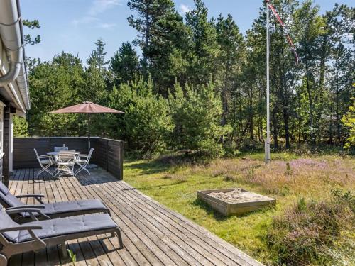 a deck with a table and chairs and an umbrella at Holiday Home Reinhardt - 800m from the sea by Interhome in Mølby