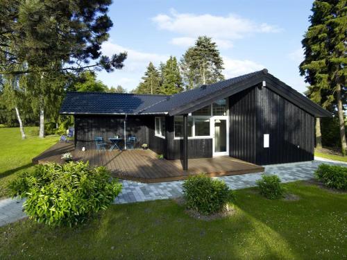 a black house with a deck in a yard at Holiday Home Antonina - 775m from the sea by Interhome in Gudmindrup