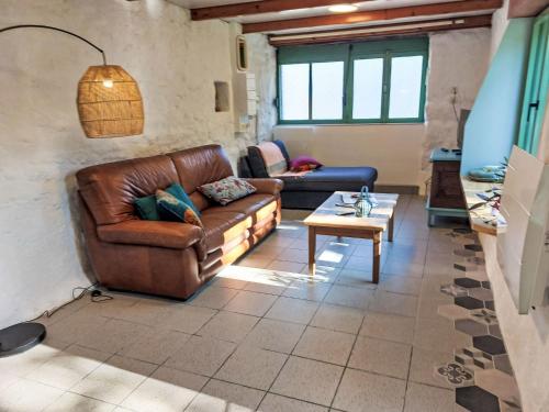 a living room with a leather couch and a table at Holiday Home La Longère by Interhome in Trémaouézan
