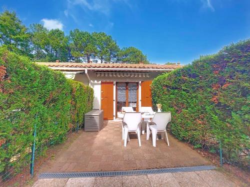 a patio with a table and chairs in front of a house at Holiday Home Les Villas de La Palmyre by Interhome in Les Mathes