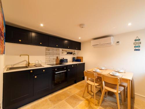a kitchen with black cabinets and a table with chairs at Holiday Home Shanty Cottage by Interhome in Mevagissey