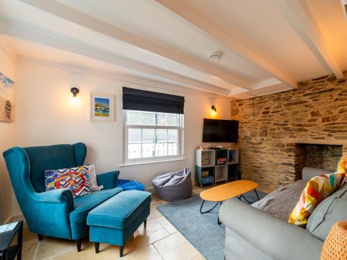 a living room with blue furniture and a stone wall at Holiday Home Shanty Cottage by Interhome in Mevagissey