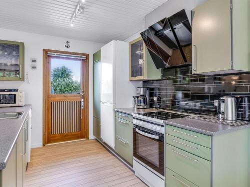 a kitchen with green cabinets and a stove top oven at Holiday Home Naema - 500m from the sea by Interhome in Østerby Havn