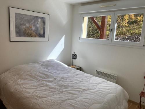a bedroom with a white bed and two windows at Appartement Le Central in Labergement-Sainte-Marie