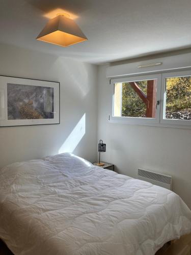 a white bedroom with a bed and two windows at La Parenthèse du Remoray in Labergement-Sainte-Marie