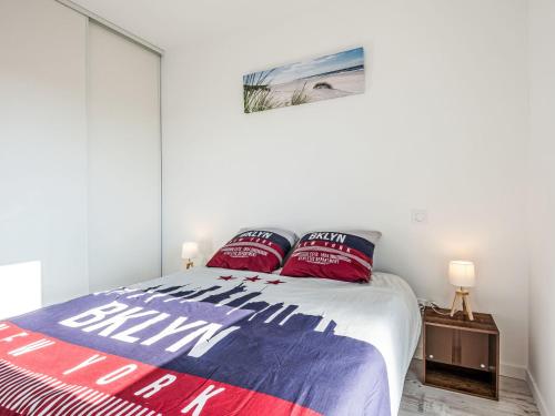 Schlafzimmer mit einem Bett mit roten und blauen Kissen in der Unterkunft Apartment le clos de la mayade by Interhome in Mimizan