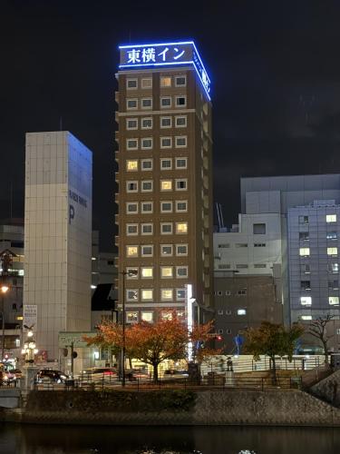 a tall building with a blue sign on top of it at Toyoko Inn Hiroshima Ekimae Ohashi Minami in Hiroshima
