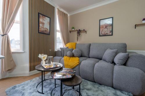 a living room with a gray couch and two tables at Open Mind Property - Cozy 4BR Flat & 12 Guests in Littlehampton