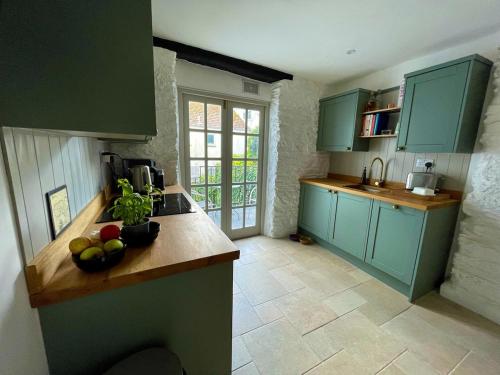 a kitchen with green cabinets and a counter with fruit on it at The Locker, 2 bed apartment in Falmouth in Falmouth