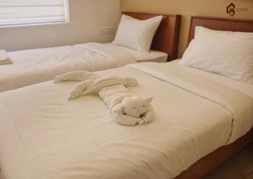 a white teddy bear laying on top of two beds at 18 Rooms By OLAN in Trichūr