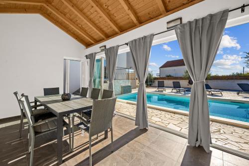 un comedor con mesa y sillas junto a una piscina en Kuca za odmor Feniks, en Polača