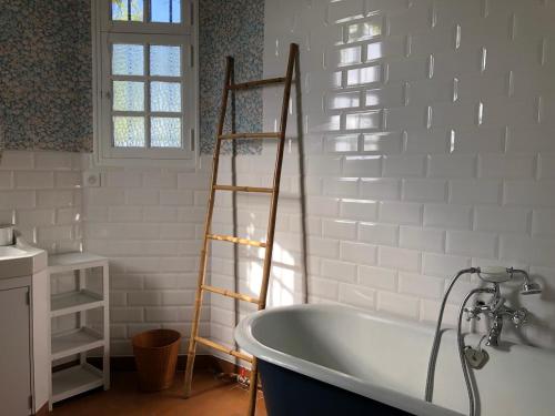 a bath tub in a bathroom with a ladder at Villa Mon But - Maison de maître du 19ème siècle in Hagetmau