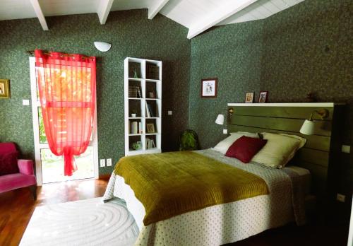 a bedroom with a bed with a red curtain and a window at Au Bal des Oiseaux in Chavagnes-en-Paillers