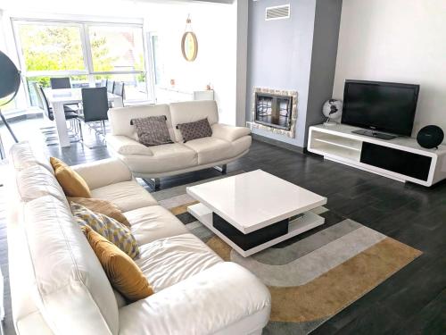 ein Wohnzimmer mit weißen Sofas und einem Fernseher in der Unterkunft L'écrin champêtre, séjour chic et cosy in Waldolwisheim