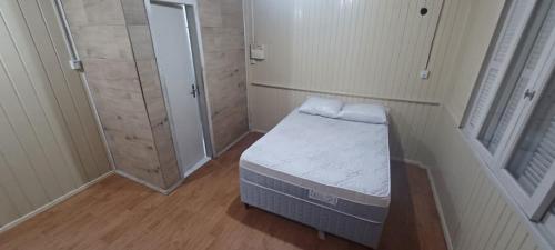 a small room with a small bed and a shower at Casa próximo á Unesc em Criciúma-SC in Criciúma