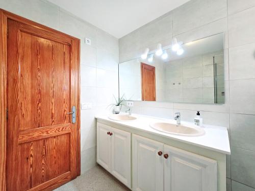 La salle de bains est pourvue de 2 lavabos et d'une porte en bois. dans l'établissement Finca Boy, à Pollença