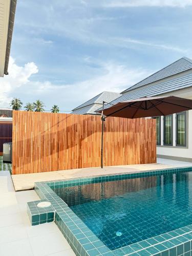 a swimming pool with an umbrella next to a wooden fence at Monkey Pool Villa Krabi Ao Nang in Ao Nang Beach