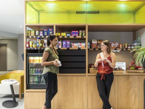 two women are playing a video game in a store at Aparthotel Adagio access Colombes La Défense in Colombes