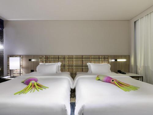 two beds in a hotel room with birds on them at Veranda Resort Pattaya - MGallery Collection, Accor Hotel in Jomtien Beach