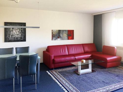 Una sala de estar con un sofá rojo y una mesa. en Gemütliche Ferienwohnung Im Disentiserhof, en Disentis