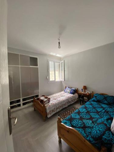 een slaapkamer met twee bedden en een raam bij Appartement Boulimat Bejaia in Matriouene