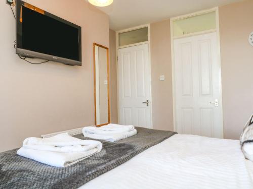 a bedroom with two towels on a bed with a flat screen tv at Valley Lodge 61 in Callington