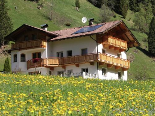 a house on a hill with a field of flowers at Cozy apartment in Außervillgraten in Außervillgraten