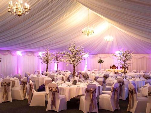 a marquee with white tables and chairs and purple lighting at Mercure Haydock Hotel in Haydock