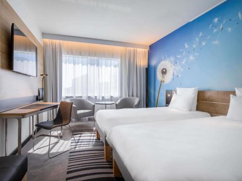 a hotel room with two beds and a desk at Novotel Wrocław Centrum in Wrocław