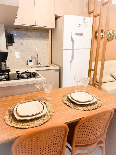 タマンダレーにあるRefugio a 50 passos do marの皿とワイングラスが置かれた木製のテーブルのあるキッチン