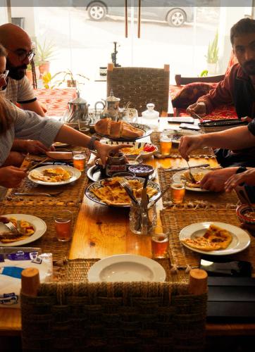 um grupo de pessoas sentadas ao redor de uma mesa comendo pizza em Imsouane Sea surf Camp em Imsouane