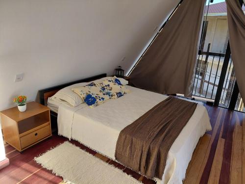 a bedroom with a bed and a table and a window at Chale Doce Refugio in Ouro Preto