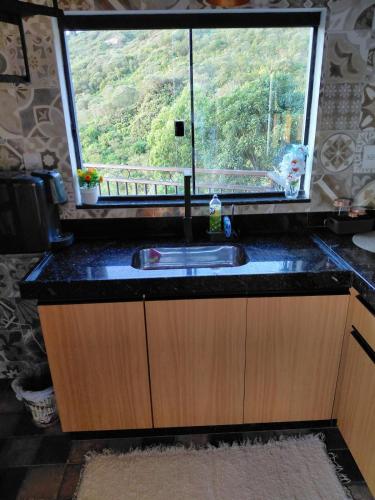 a kitchen counter with a sink and a window at Chale Doce Refugio in Ouro Preto