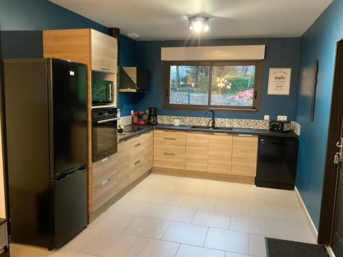 eine Küche mit einem schwarzen Kühlschrank und einem Fenster in der Unterkunft L Atelier Veulais in Veules-les-Roses