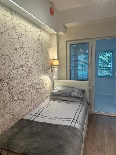 a bedroom with a bed against a wall at Unique space in Edgware in Stone Grove