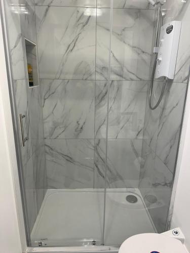 a shower with a glass door in a bathroom at Unique space in Edgware in Stone Grove
