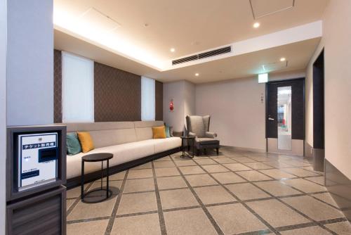 a living room with a couch and a chair at HOTEL MYSTAYS Gotanda in Tokyo