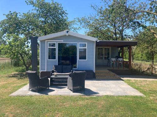 a small blue house with chairs and a porch at B&B Landlust in Kapel-Avezaath