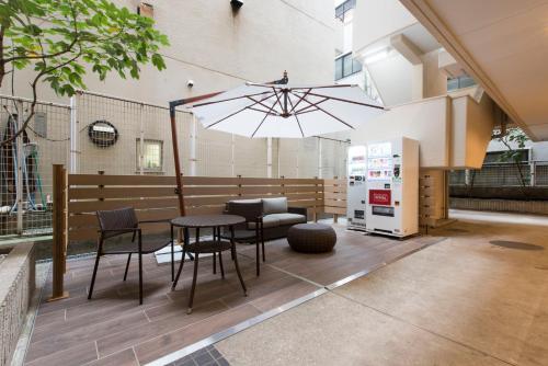 a patio with a table and chairs and an umbrella at HOTEL MYSTAYS Gotanda in Tokyo