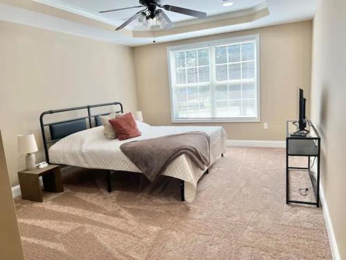 里士满Cozy Home on Golf Course Near I75 and Bucee's的一间卧室，里面有一张床和一个吊扇
