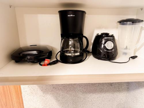 タマンダレーにあるRefugio a 50 passos do marの棚の上のコーヒーメーカーとカメラ