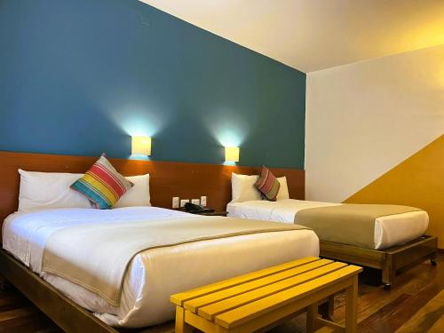 Una habitación de hotel con dos camas y un banco. en Usgar San Pedro Boutique, en Cusco