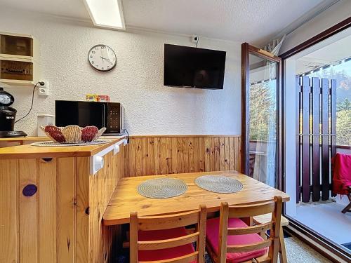 une cuisine avec une table en bois et une horloge au mur dans l'établissement Studio Résidence des Montagnes by Interhome, à Bellevaux
