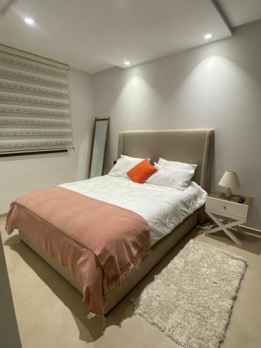 a bedroom with a large bed with an orange pillow at Cozy apartment in Kenitra