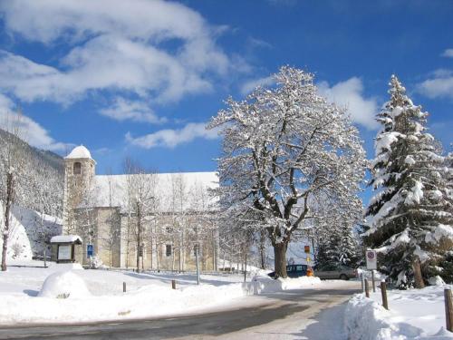 un edificio cubierto de nieve con un árbol y una calle en Gemütliche Ferienwohnung Im Disentiserhof, en Disentis