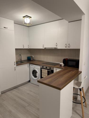 a kitchen with white cabinets and a washer and dryer at Millo Apartament in Bucharest