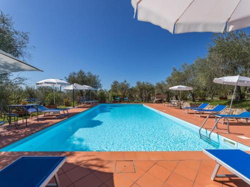 a swimming pool with chairs and umbrellas at Apartment La Foresta-3 by Interhome in Quercegrossa