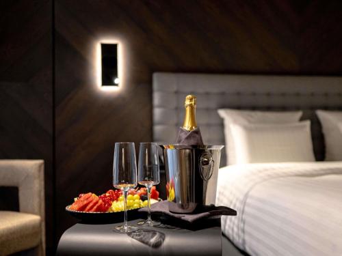 a table with a bottle of champagne and wine glasses at Pullman Riga Old Town - Renovated 2025 in Rīga