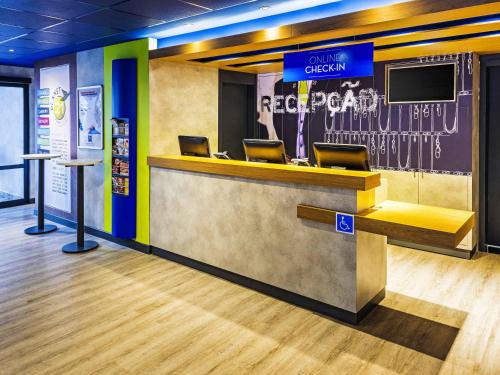 a lobby with a counter with chairs and a tv at ibis budget SP Frei Caneca in Sao Paulo