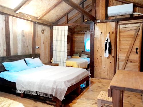 two beds in a room with wooden walls at Tiny houses Genacvale in Martvili